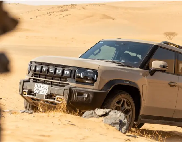 Jetour SUV on a desert dune in soft afternoon light